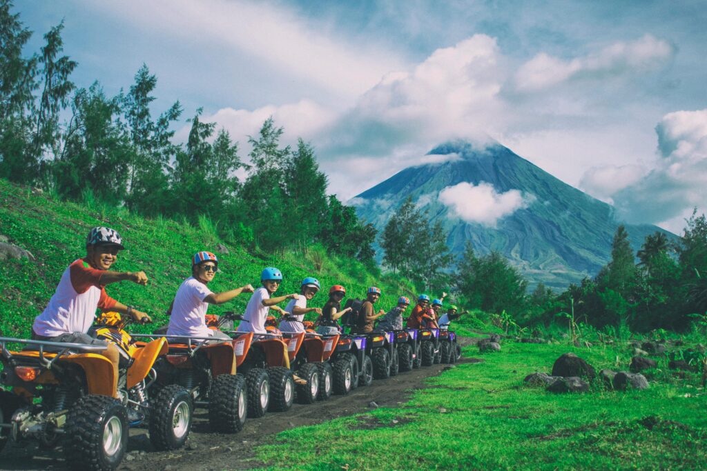 Group of friends enjoying an ATV ride with Mayon Volcano in the background.